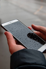 phone in men's hands in the rain