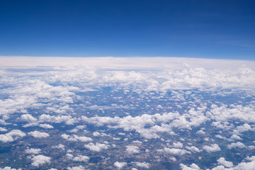 Beautiful view from airplane window above the clouds. Bright blue sky and white clouds. Skyline background with copy space.