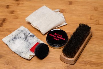 Tools and materials for putting a fine polish on dress shoes.  Presented on a wood floor surface ready to be used.  Various Spaces for copy and easily editable text on the Wax container.