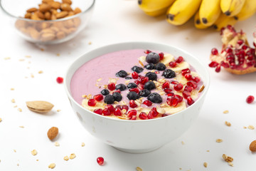 Breakfast smoothie bowl with yogurt, granola, pomegranate, blueberries, banana, almond and chia seeds.
