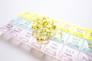 Organizer for medical pills on a white isolated background close-up. Organization of taking pills of the day. Transparent vitamins lie nearby.