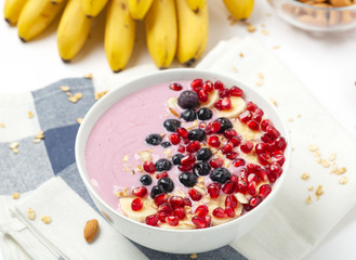 Breakfast smoothie bowl with yogurt, granola, pomegranate, blueberries, banana, almond and chia seeds.