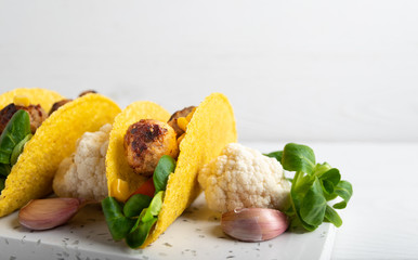 Taco with vegan meatballs and vegetables, on a white background.