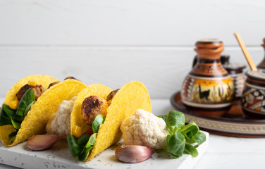 Taco with vegan meatballs and vegetables, on a white background.