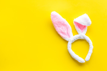 Easter bunny concept. Toy rabbit's ears for head on yellow background top-down copy space