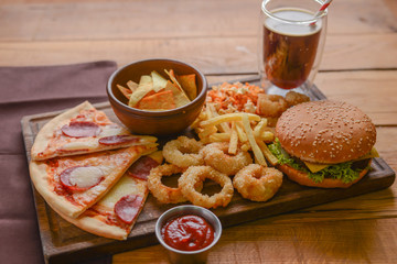 Fast food concept with greasy fried onion rings, burgers, and pizza with french fries and popcorn. Junk food concept.