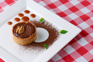 Chocolate creme brulee with cocoa powder, walnuts and mint leaf. Traditional French vanilla cream dessert.