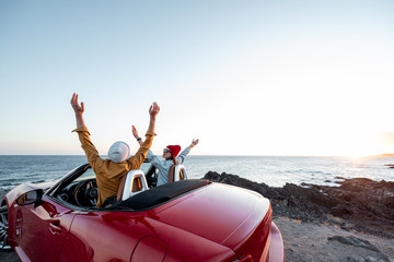 Couple enjoying beautiful view on the ocean, traveling by convertible car near the ocean on a...
