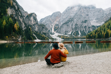 couple in love man and woman are sitting on the shore of lake lago di braies in Italy. men's and women's clothing.