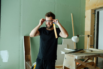 Happy bearded man standing with corner ruler in rennovating apartment.