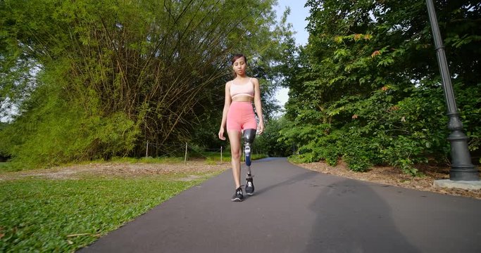 Leg Amputated Asian girl walking inside bamboo garden after finishing her morning workout session