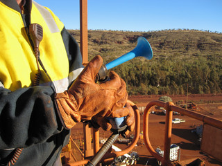 Male rigger hand wearing a safety glove using a signal air horn to direct a crane operator while working at construction site Perth Australia 