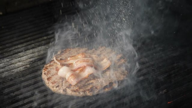 Cooking beef and pork patty for burger. Steam rising up. Slow motion. Meat roasted on fire barbecue kebabs on grill. Grilled burger cutlet beef minced meat patties or frikadeller on grill. Street food