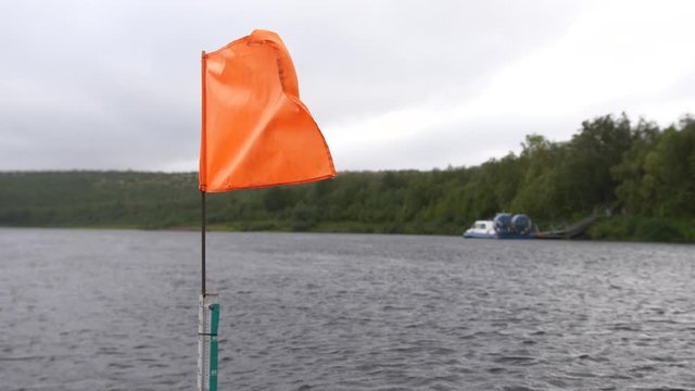 A flag in windy conditions in the middle of a large river