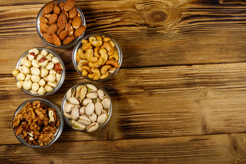 Assortment of nuts on wooden table. Almond, hazelnut, pistachio, walnut and cashew in glass bowls. Top view, copy space. Healthy eating concept