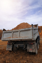 A dump truck unloads sand in the construction site.