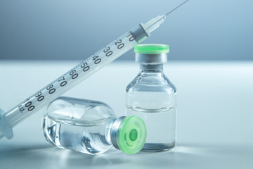 Vaccine in vial and syringe close-up on a white table gray background, medical concept, laboratory, subcutaneous injection vaccination, dose. Disease treatment immunization.