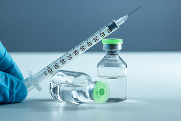 Vaccine in vial and syringe close-up on a white table gray background, medical concept, laboratory,...