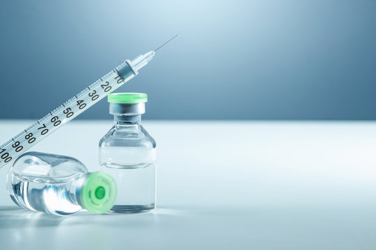 Vaccine in vial and syringe close-up on a white table gray background, medical concept, laboratory, subcutaneous injection vaccination, dose. Disease treatment immunization.