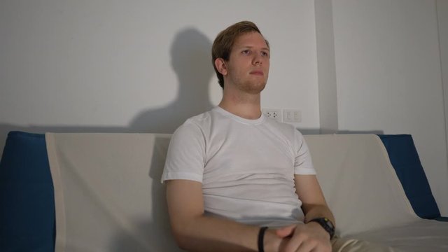 Young Man Sitting on Couch and Watching TV Alone at Night