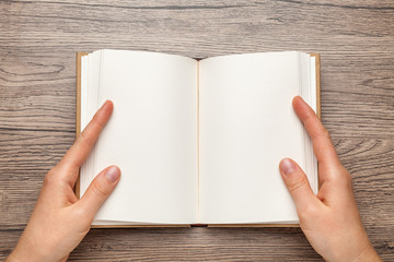 A5 open book mockup with hands. Empty template of page. Blank for design. On wooden background.