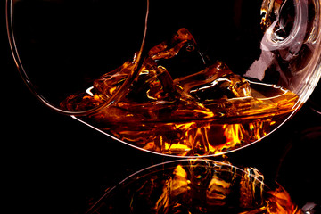 Whiskey with ice in glass isolated on black background
