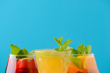 Three tropical mixed drinks with lime and lemon and mint leaves served in different glasses on rustic wooden table.