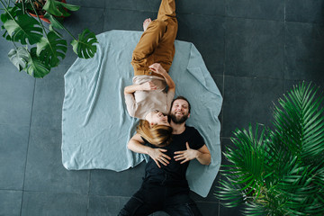 Happy couple lying on a floor covered with sheets. They just moved in.