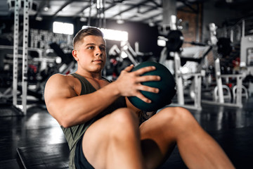 Naklejka na ściany i meble Young attractive muscular gen z athlete doing weighted ball abs exercises