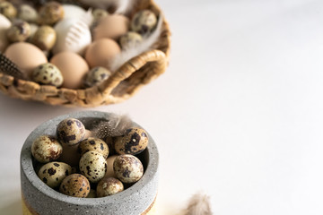 White and brown Easter eggs and feathers in a basket on white background. Natural healthy food and organic farming, easter and spring concept.