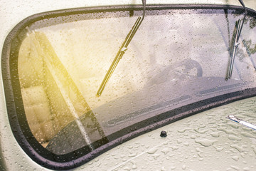 Windshield of a retro car after rain. Wet glass of a classic car with sunbeams.