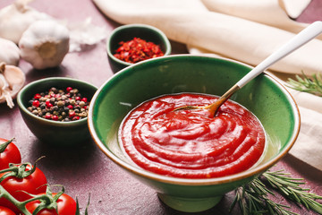 Bowl with tomato sauce on color background