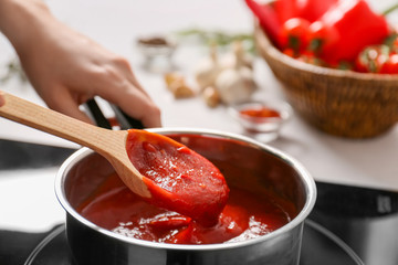 Woman preparing tomato sauce in saucepan
