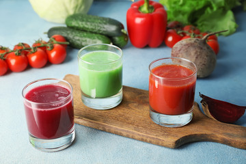 Glasses of fresh vegetable juices on color background
