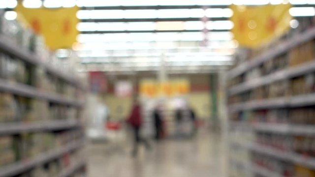People are shopping in a supermarket, defocused blurred background People with shopping carts.