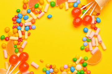 Frame made of tasty candies on color background
