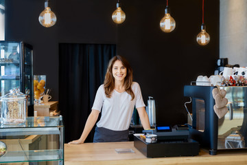 Female coffee shop owner standing behind a bar counter