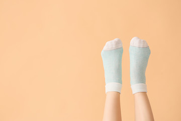 Legs of young woman in socks on color background