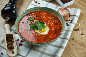 Appetizing red soup on meat broth with vegetables and quail egg. Close up view. Tasty food