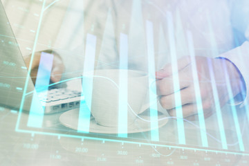 Double exposure of graph with man typing on computer in office on background. Concept of hard work.