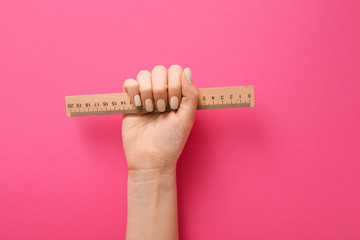 Female hand with ruler on color background