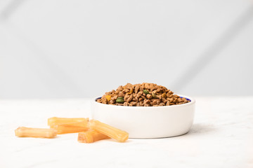 Bowl with dry pet food on table