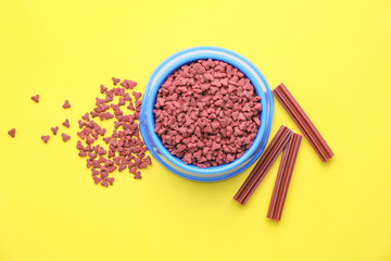 Bowl with dry pet food on color background