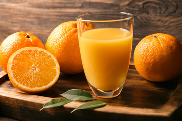 Glass of fresh orange juice on wooden background