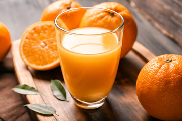 Glass of fresh orange juice on wooden background