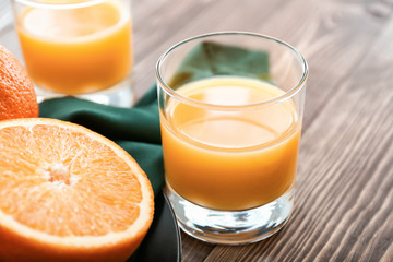 Glass of fresh orange juice on wooden background
