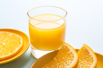 Glass of fresh orange juice and fruit on table