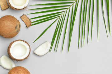 Fototapeta na wymiar Ripe coconuts and palm leaf on light background
