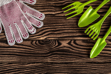 Gardening tools concept. Spade, fork, rake and gloves on wooden background with space for text flat...
