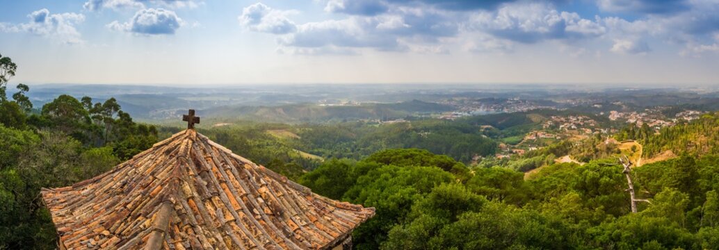 Panoramic shot of the Bucaco forest with an old chapel roof in the foreground